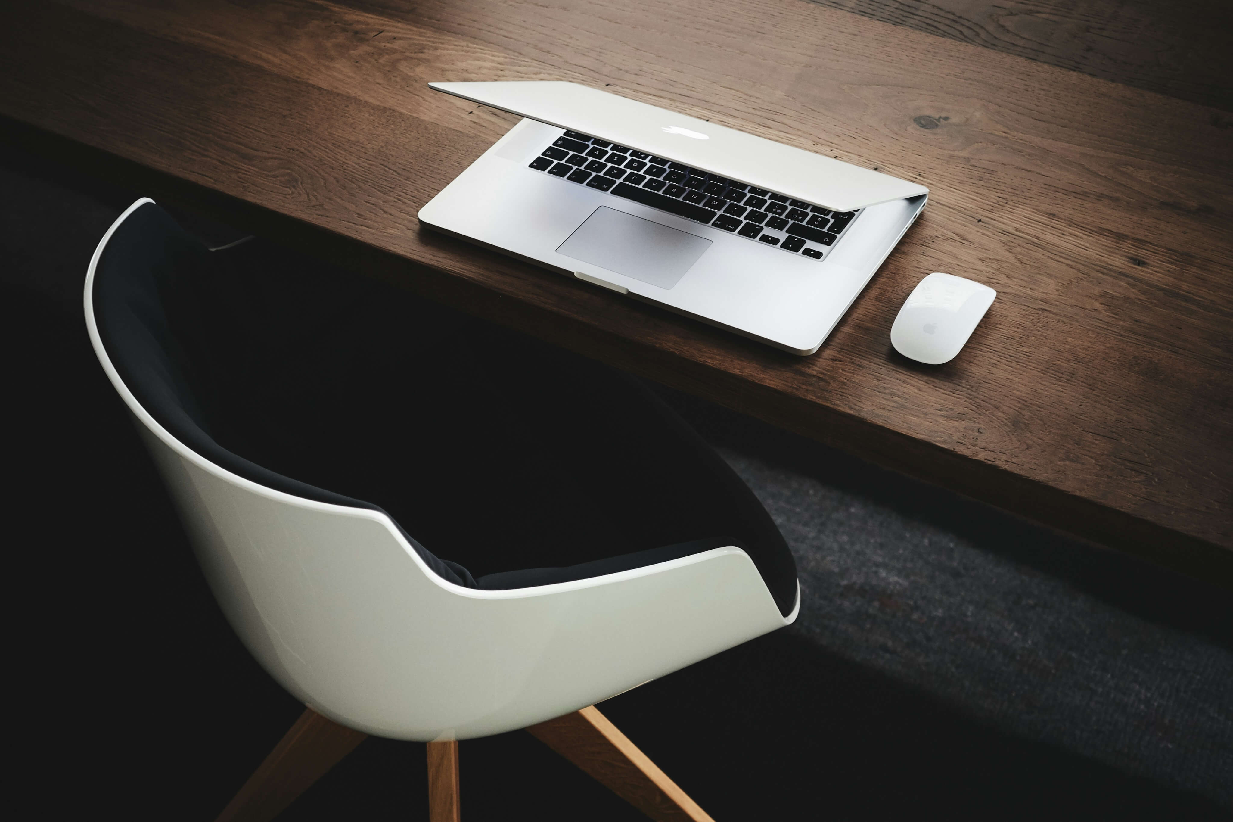An image showing a laptop on the table with a chair